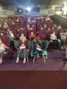 Zdjęcie przedstawia dzieci siedzące w kinie.