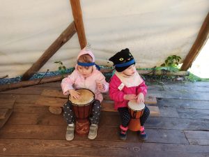 Zdjęcie przedstawia dwie dziewczynki, które grają na bębnach.